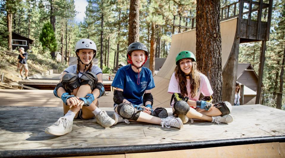 Three children in skateboard gear at summer camp