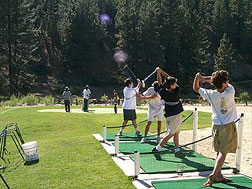 Campers swinging golf clubs at summer camp