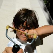 Boy shooting a sling shot at outdoor camp